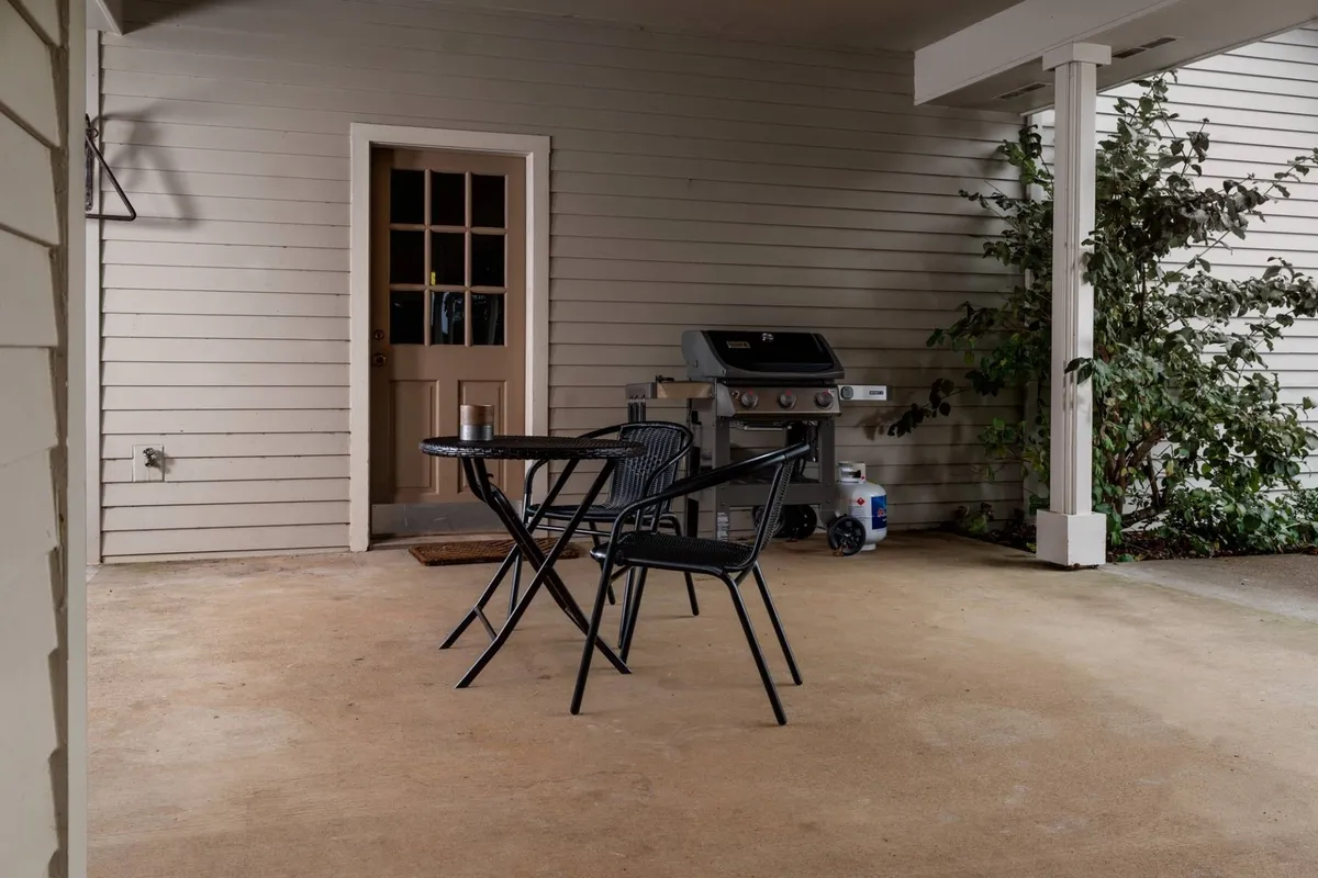An inviting outdoor patio area is shown, with a set of table and chairs and a grill beside the entrance doorway. The setup suggests opportunities for outdoor dining and gathering after a day of exploring the region.
