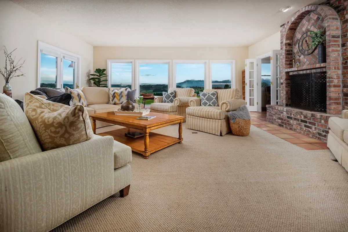 An inviting seating area with cozy chairs and a fireplace, all centered around large windows that reveal a breathtaking outdoor panorama. The design encourages group gatherings and relaxed conversation while keeping the beautiful view in constant sight.